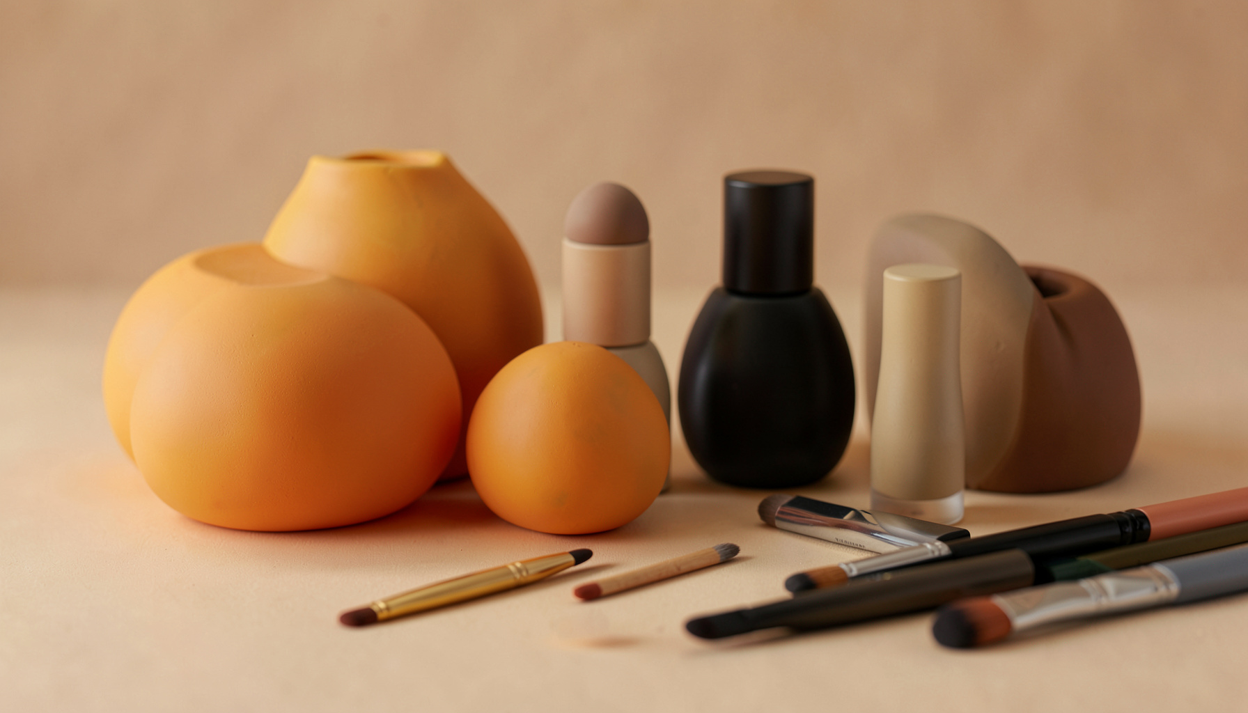 Formas redondeadas en tonos dorados y negros, con frascos de cosmética y pinceles de maquillaje sobre una superficie suave, atmósfera cálida y elegante.